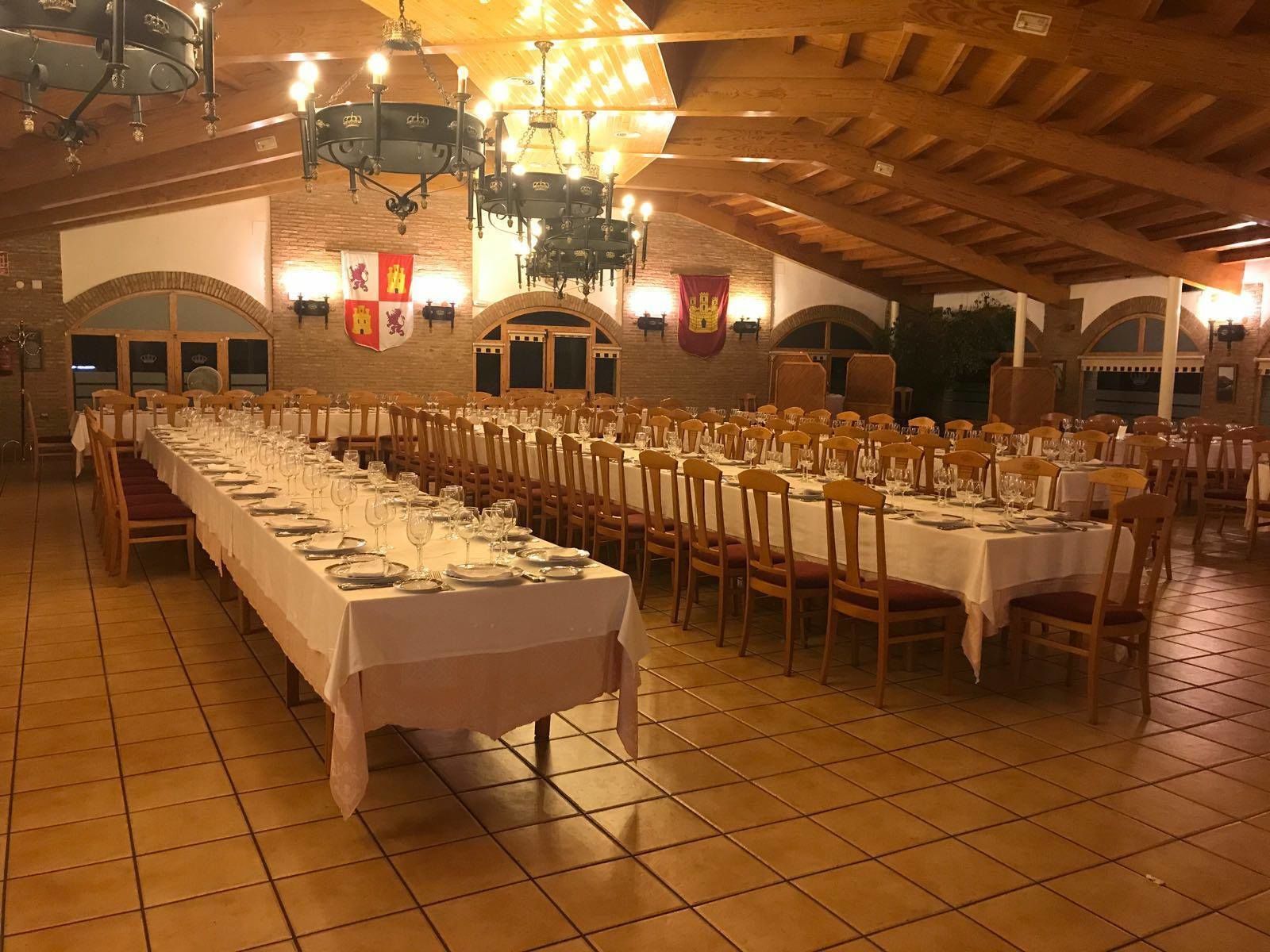 Un salón de banquetes con largas mesas dispuestas para comer, sillas de madera y candelabros.