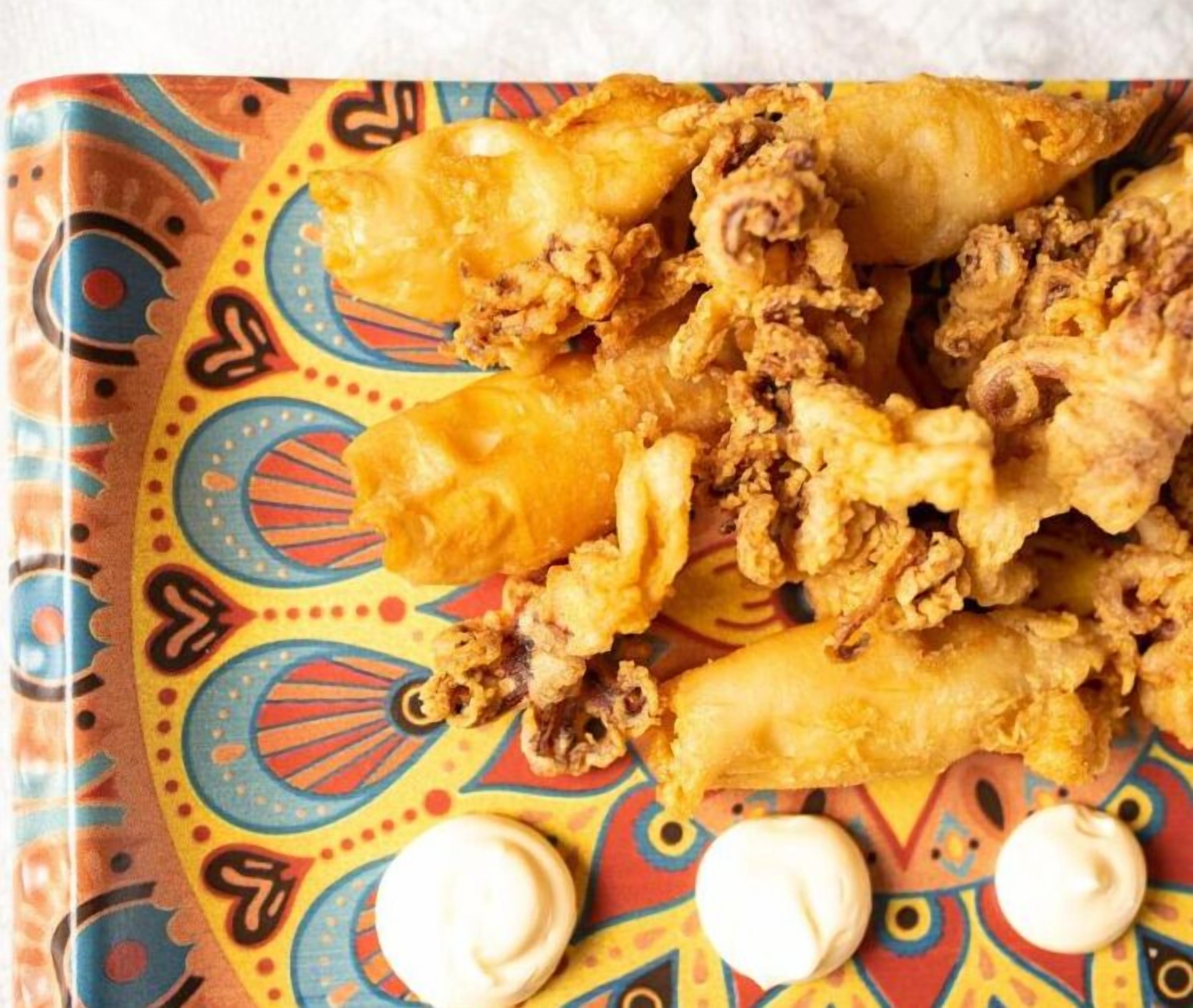 A plate of fried food with dipping sauces.