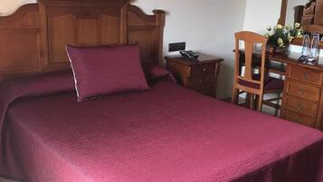 Una cama bien hecha con cabecera de madera y colcha roja.