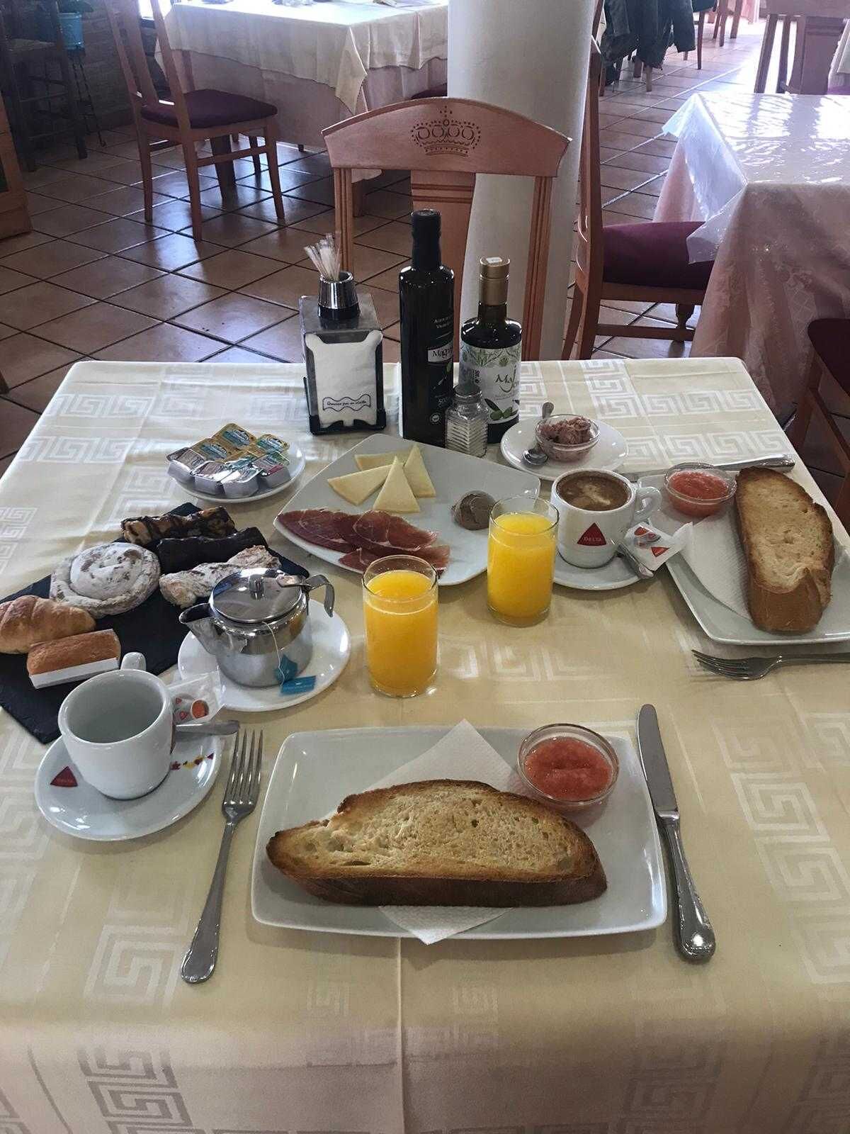 A breakfast table with various food items, including bread, cheese, and beverages.