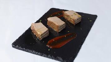 A dessert on a black slate plate with a red sauce and garnish.