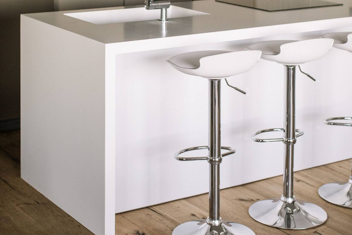 Uma cozinha moderna com uma ilha central, eletrodomésticos de aço inoxidável e banquetas.