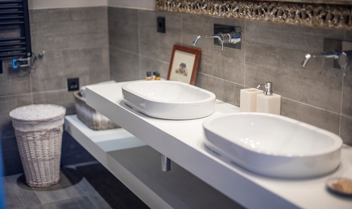 A modern bathroom with two large white sinks, a mirror, and a framed photo on the wall.