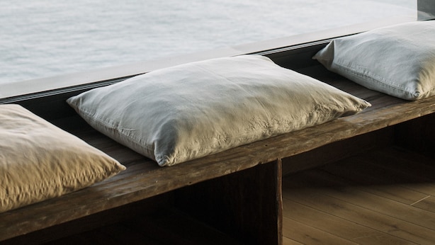 A wooden bench with pillows by a window overlooking a coastal view. - Apartaments Cap Sa Sal (Begur)