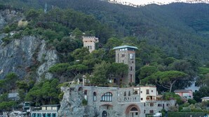 A coastal building with a stone tower, situated on a cliff overlooking a beach. - La Casa del Gigante Luxury Collection (Monterosso al Mare)