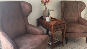 Two brown armchairs, a small wooden side table with a vase and a book, and two framed portraits on the wall. - Hjørring Kro (Hjørring)