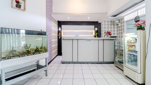 Zona de recepción con un acuario, un refrigerador y un mostrador.