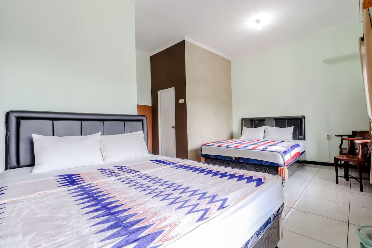 A hotel room with two beds, a wooden headboard, a small table, and a chair.