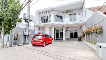 A two-story building with a sign indicating it is a hotel. There is a red car parked in front.