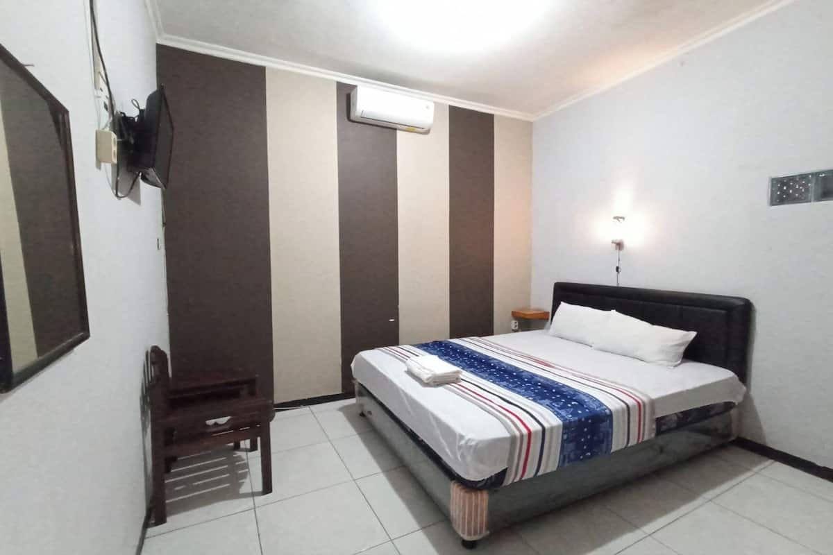 A bedroom with a bed, bedside table, and a desk with chair.