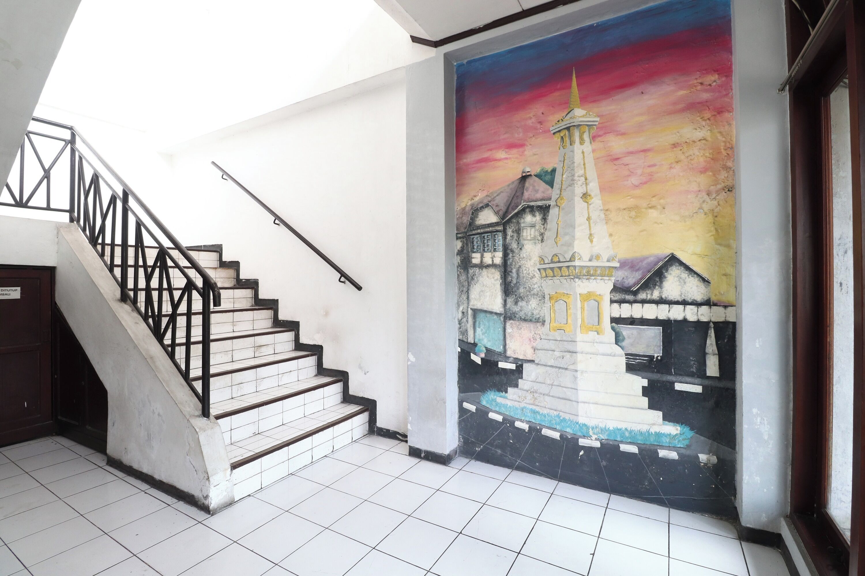 A staircase with a handrail, leading to a tiled floor.