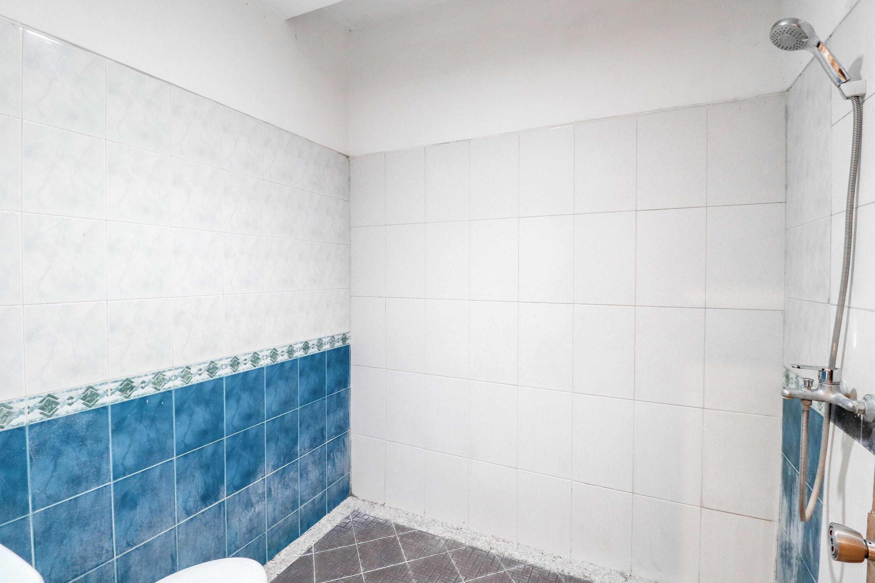 A bathroom with white and blue tiles, a shower, and a toilet.