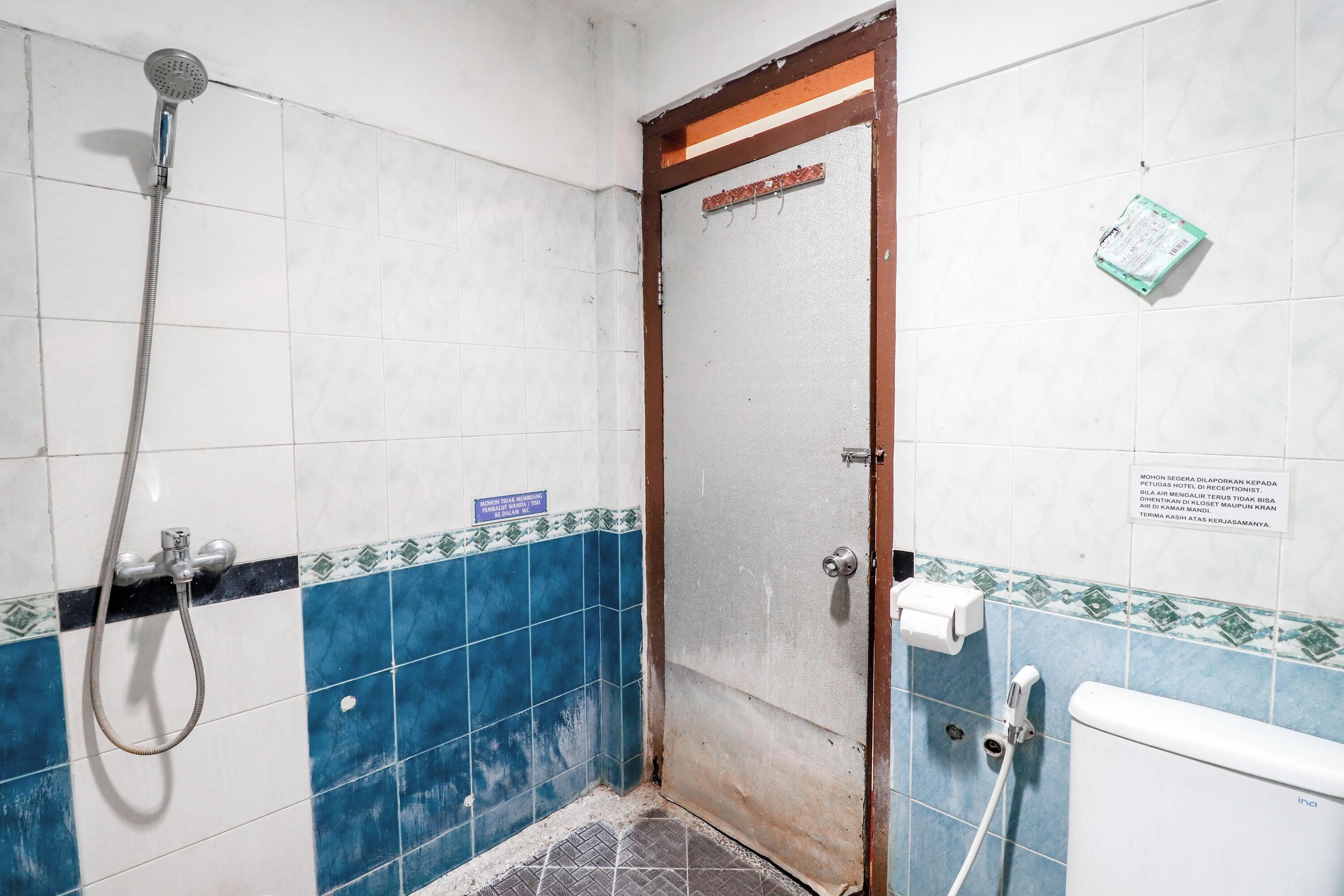 A bathroom with a shower, toilet, and a door with a sign.