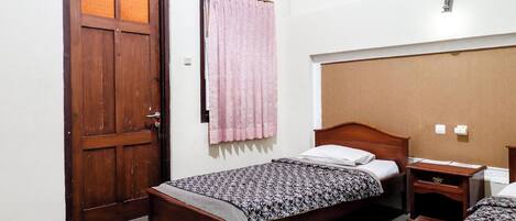 A room with two wooden beds, a wooden nightstand, a wooden door, and a pink curtain.