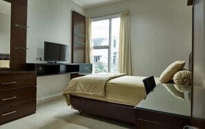 A bedroom with a bed, a TV, a dresser, and a window. - Bendungan Hilir Residence (Jakarta)