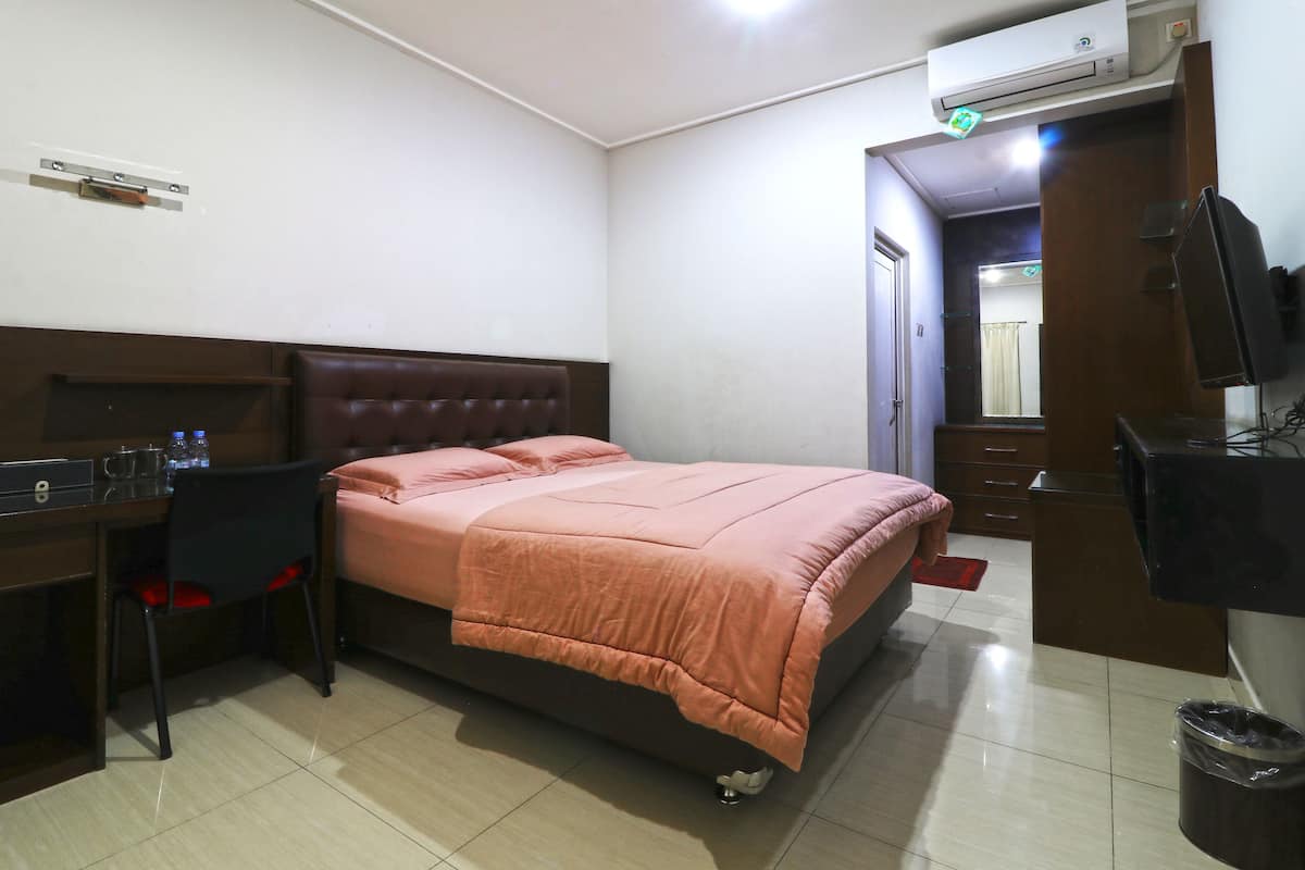 A hotel room with a bed, desk, chair, and a television.