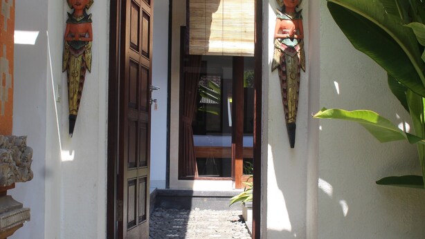A staircase leading to a door with traditional decor and a plant on the right. - Jukung Villas Kuta (Kuta)
