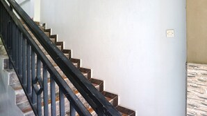 Eine Treppe mit schwarzen Geländern und Steinstufen, die zu einer Zwischenebene mit einer hellen Wand und einer Steckdose führt.