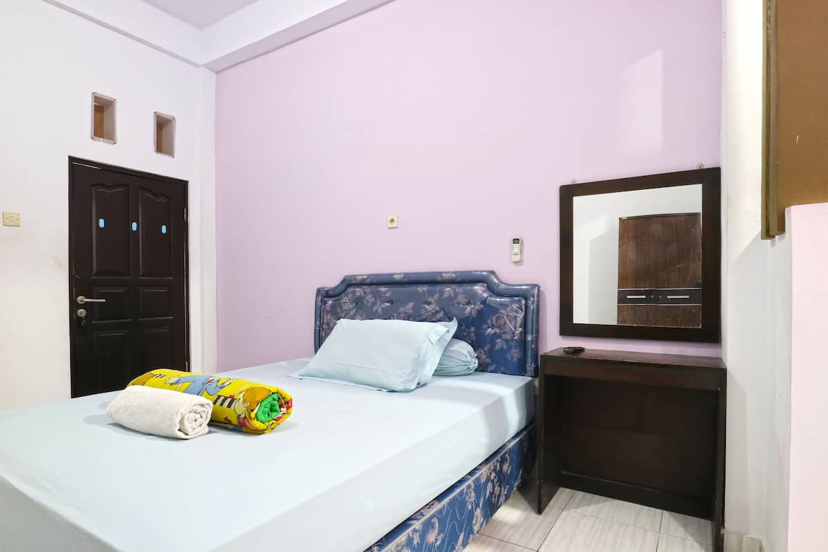 Un dormitorio con cama, mesita de noche, espejo y puerta.