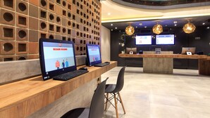 Ein Empfangsschalter mit zwei Laptops, eine Ziegelwand mit runden Aussparungen und ein modernes Interieur.