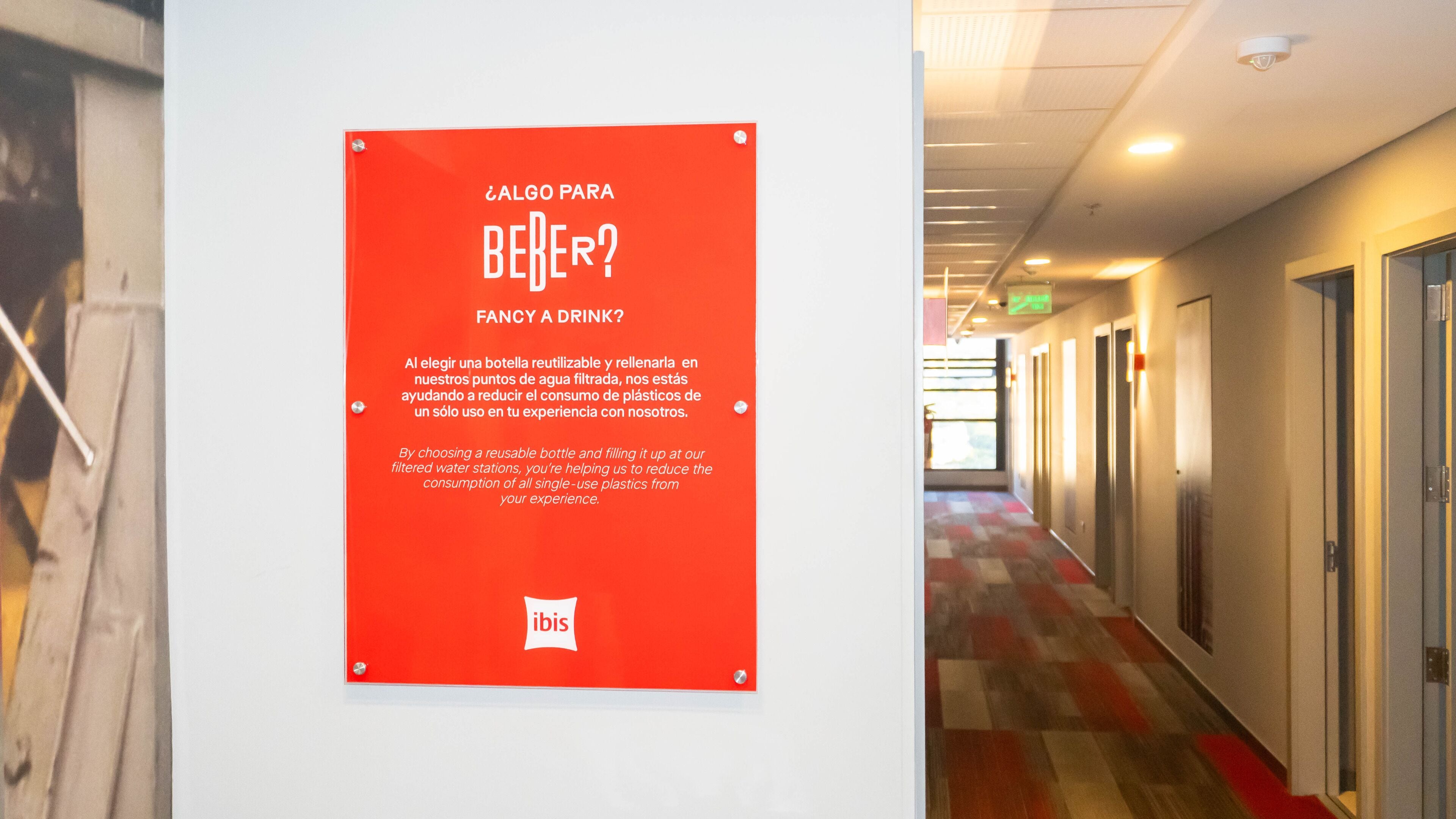 Een rood bord met tekst in het Spaans op een muur in een gang.
