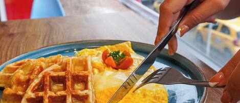 A plate with waffles and an omelette on a table with a view of a cityscape.