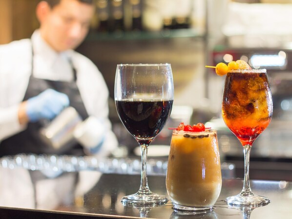 Tres vasos de diferentes bebidas sobre una barra.