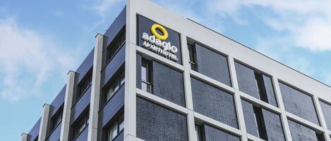 A modern building with a sign for 'Adagio APART HOTEL'.