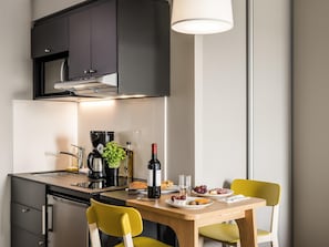 Une cuisine moderne avec un coin repas, comprenant une machine à café, une bouteille de vin et des assiettes de nourriture.