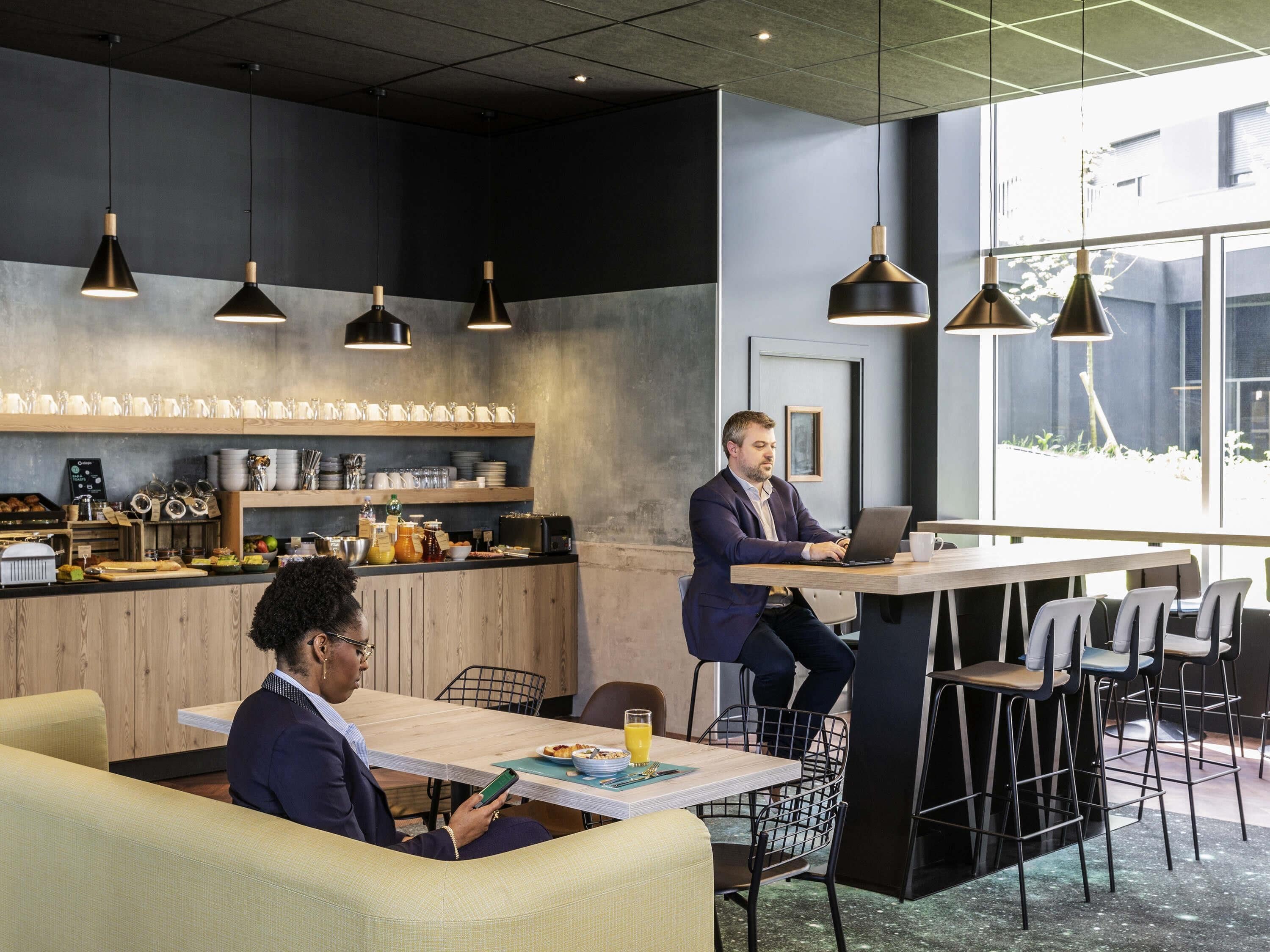 Un espace de bureau moderne avec une grande table, des chaises et une personne travaillant sur un ordinateur portable.