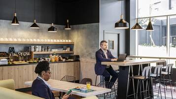 Un espace de bureau moderne avec une grande table, des chaises et une personne travaillant sur un ordinateur portable.