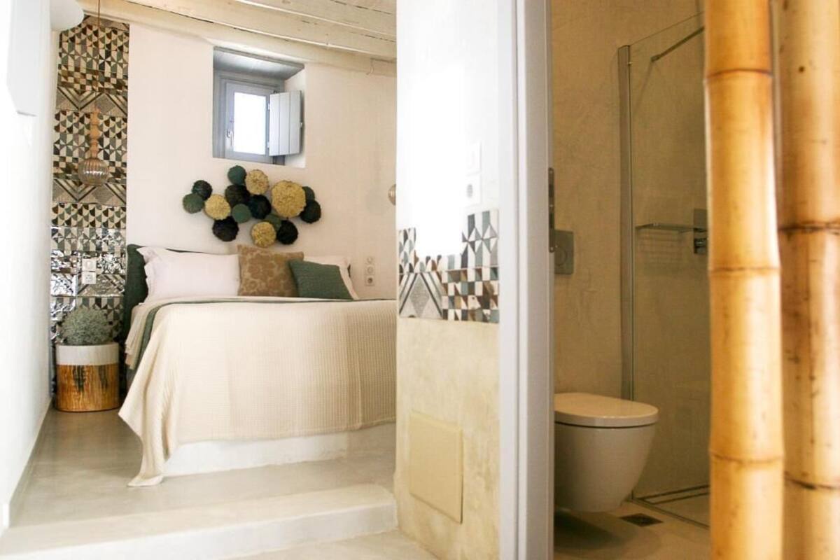 Une chambre à coucher comprenant un lit, un élément décoratif fixé au mur, et une salle de bain avec des toilettes et une douche.