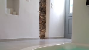 Un baño moderno con pared decorada con piedra, una bañera empotrada y una toalla en el suelo.