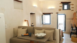 Una sala de estar con un sofá, una mesa con un tazón y una taza, y una ventana con vistas.