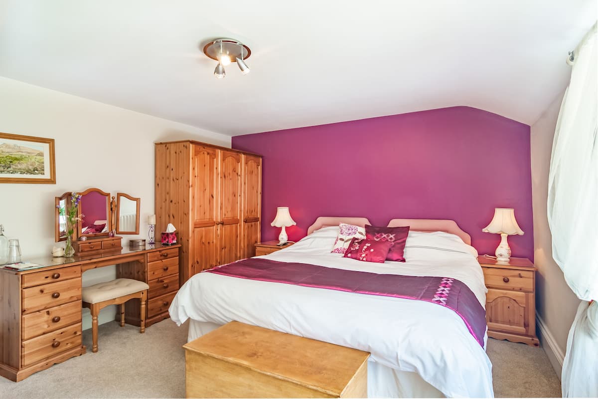 Une chambre à coucher comprenant un lit, une armoire en bois, un bureau et un banc.
