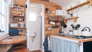 A kitchen with wooden shelves, a sink, a stove, and various kitchen utensils. - Cadleigh Manor B&B (Ivybridge)