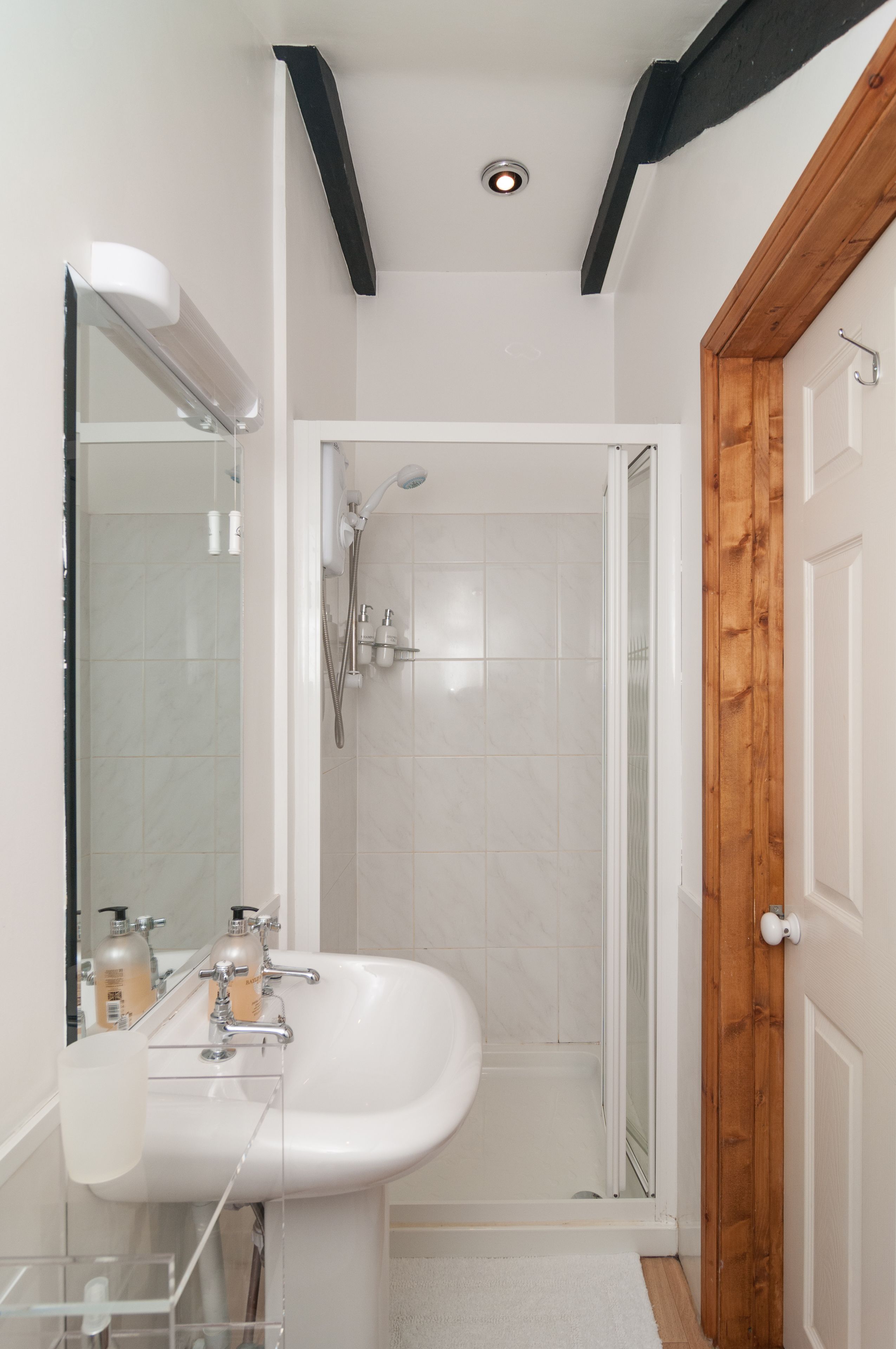 A bathroom with a white sink, mirror, and shower.