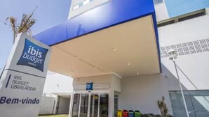 Exterior de un hotel ibis budget con techo azul y cartel que indica el nombre y la ubicación.
