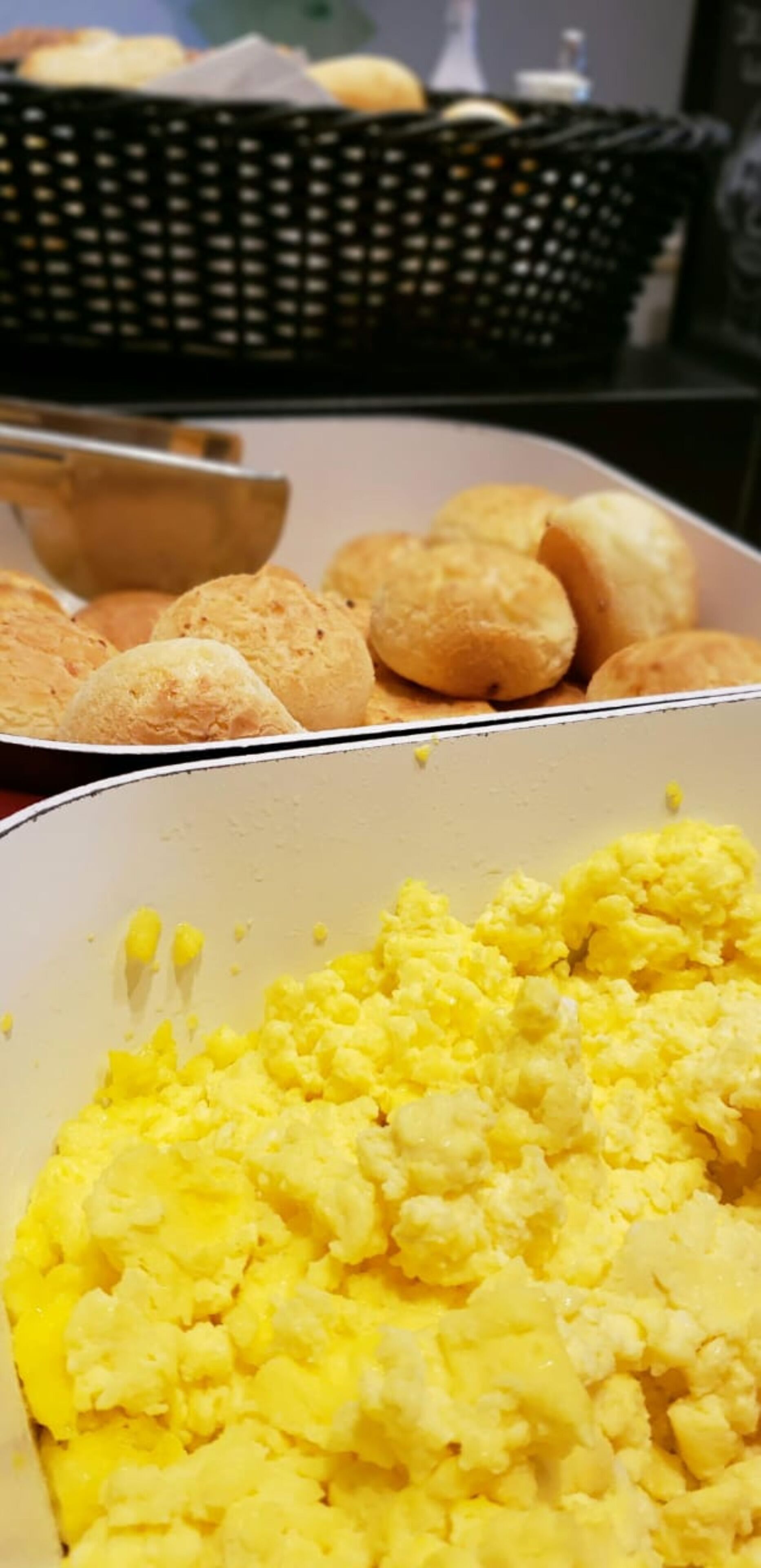 Uma bandeja de pastelaria dourada e um recipiente com ovos mexidos.