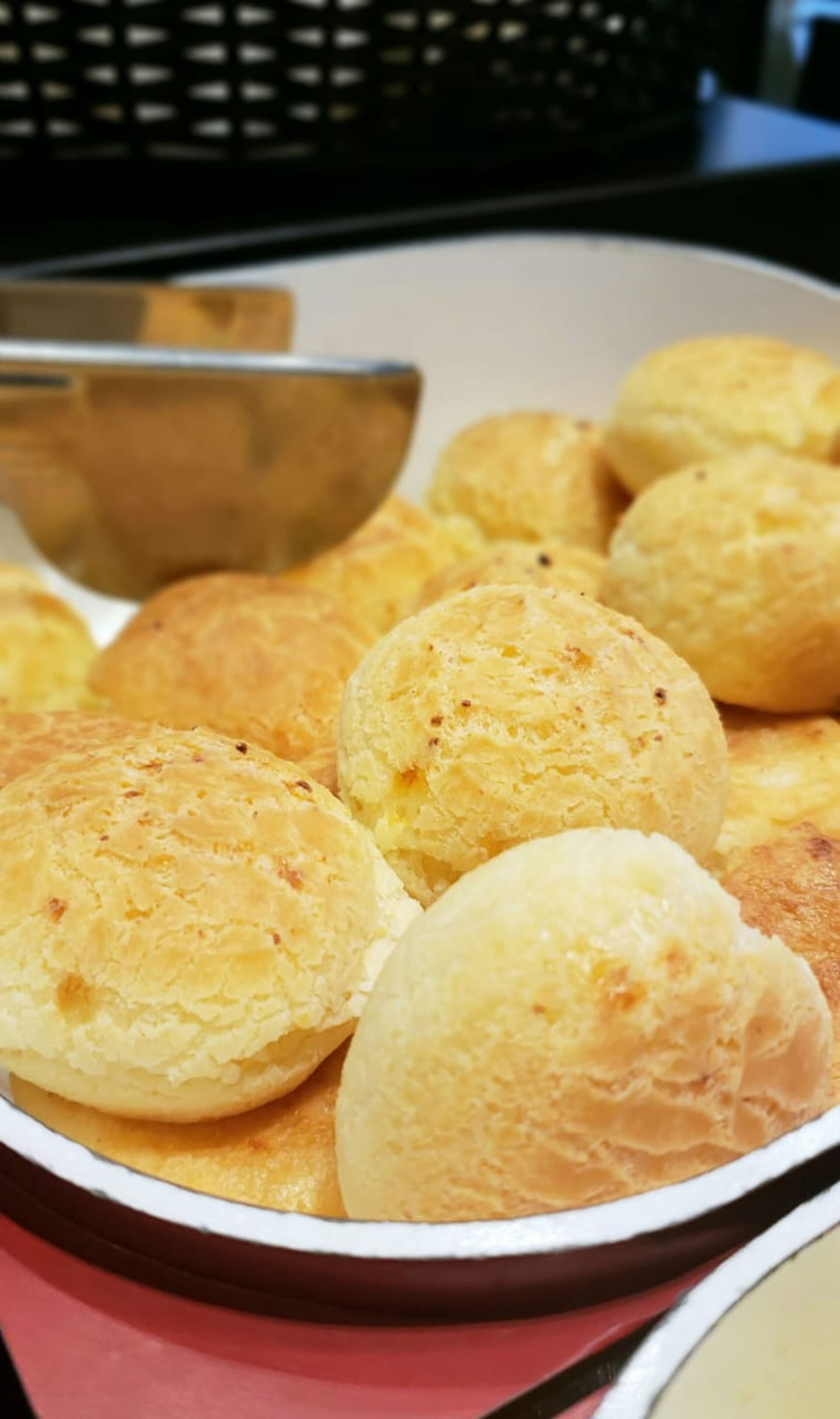 Eine Schale goldbraune Gebäckstücke, vermutlich Käsebrot, in einer weißen Schale mit rotem Rand.