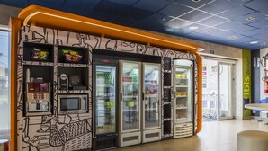 Un quiosco de autoservicio con una cafetera, microondas y vitrinas refrigeradas.