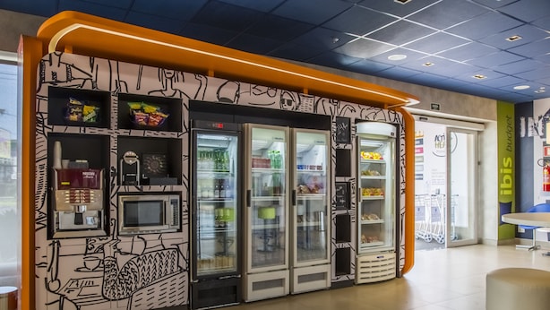 Un quiosco de autoservicio con una cafetera, microondas y vitrinas refrigeradas.