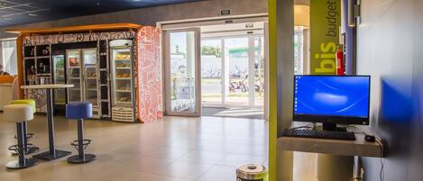 A modern interior with a computer desk, a vending machine, and a seating area with stools.