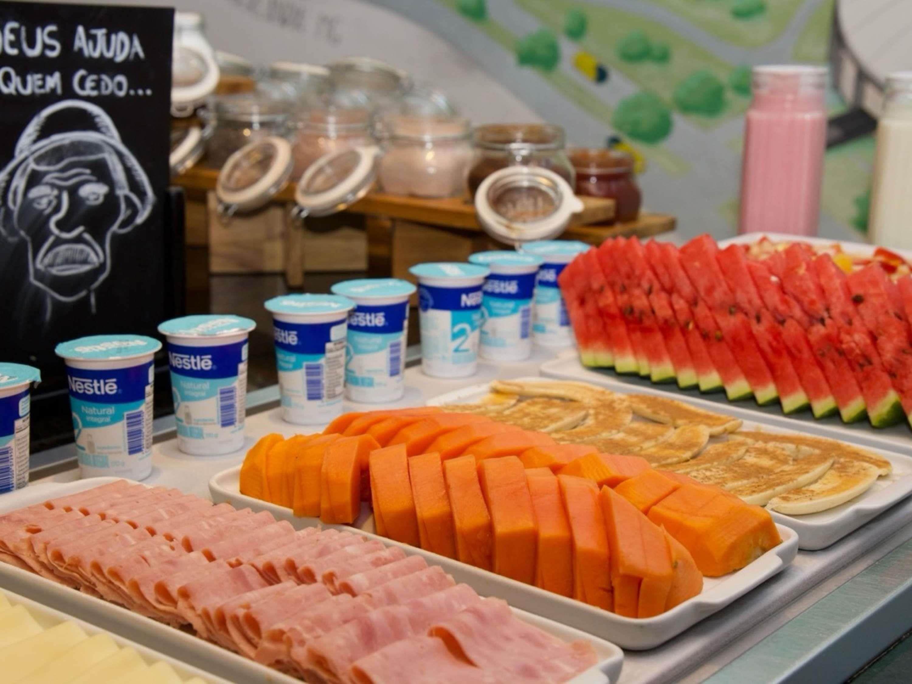 Buffet com diversos alimentos, incluindo presunto fatiado, cenouras e melancia.