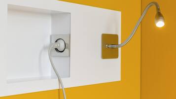 A bathroom with a white wall, a yellow accent wall, a showerhead, and a light fixture.