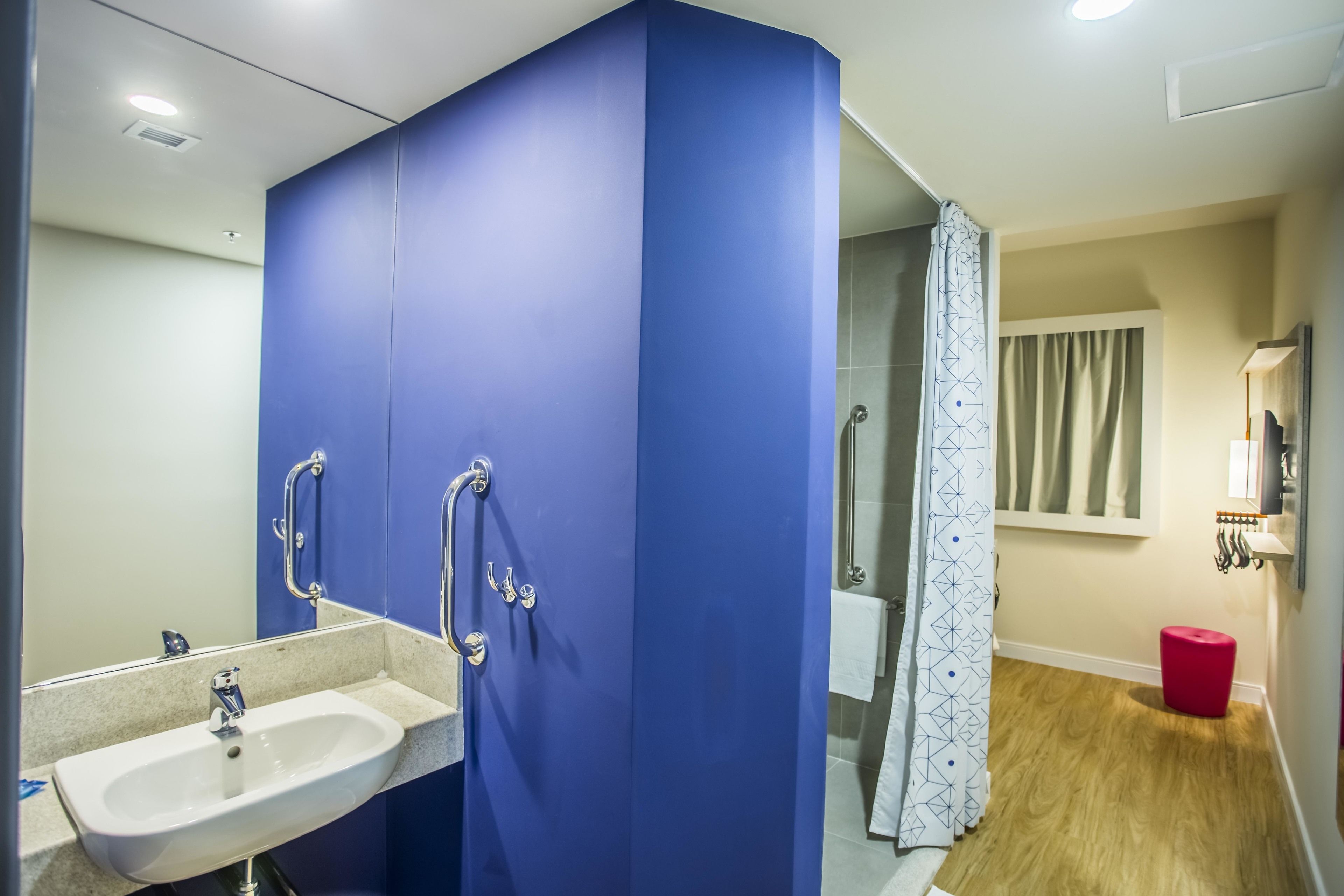 A bathroom with a sink, mirror, and shower area.
