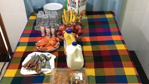 Ein Frühstücksbuffet mit verschiedenen Speisen und Beilagen auf einer bunten, karierten Tischdecke.