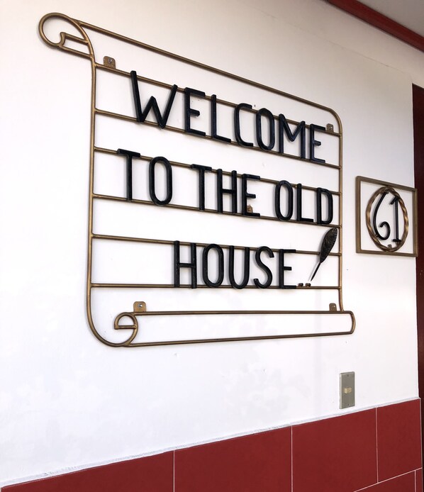 A metal sign with the text "WELCOME TO THE OLD HOUSE." - Casa Hotel la Casa Vieja (San Salvador)