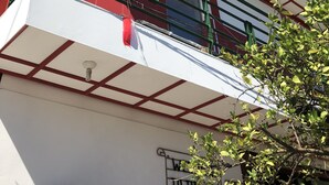 Ein Gebäude mit weißer Fassade, roten Akzenten und grünen Geländern.