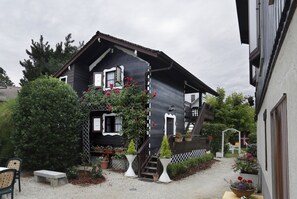 A black wooden house with a white fence, a staircase, and potted plants. - Hôtel A l'Ombre des Marronniers (Thonon-les-Bains)